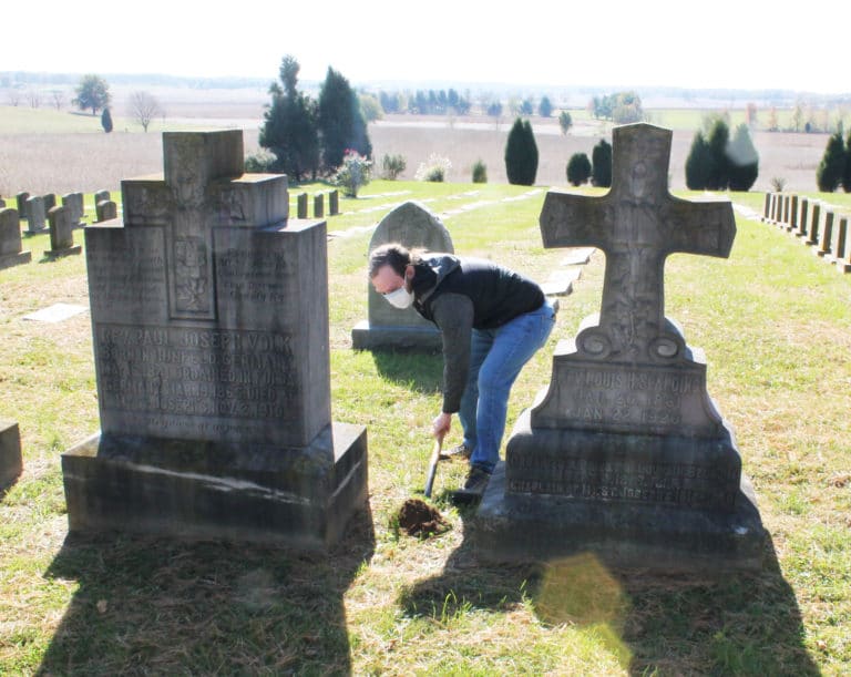 Edward Wilson, director of the Archives, digs a hole between the graves of Father Paul Volk, left, and Father Louis H. Spalding, who was the chaplain at the Mount from 1914 until his death in 1920.