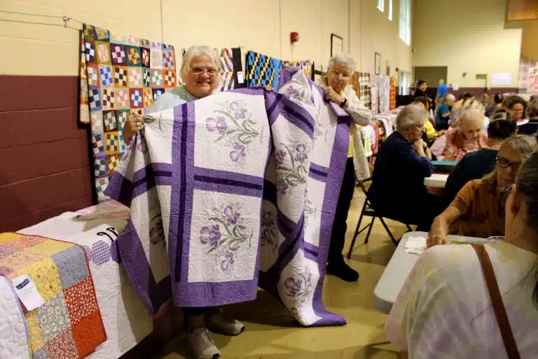 Denise Smith of Hardinsburg was pleased after winning her “Lovely Lilac” quilt. Sister Jane Falke helps hold it up. Denise Smith of Hardinsburg was pleased after winning her “Lovely Lilac” quilt. Sister Jane Falke helps hold it up.