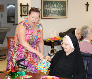 Sister Helen Leo Ebelhar, right, smiles as she draws a number out of the bag held by Debbie Dugger, activities coordinator for the sisters in Saint Joseph Villa. The sisters had a chance to win door prizes throughout the luau.