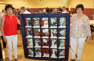Karen Calhoun McCarty, A74, left, holds up the quilt she made that was won by Phyllis Costello Bresnik, A66.
