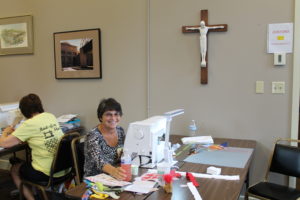 An attendee at the retreat smiles as she sits at her sewing machine.