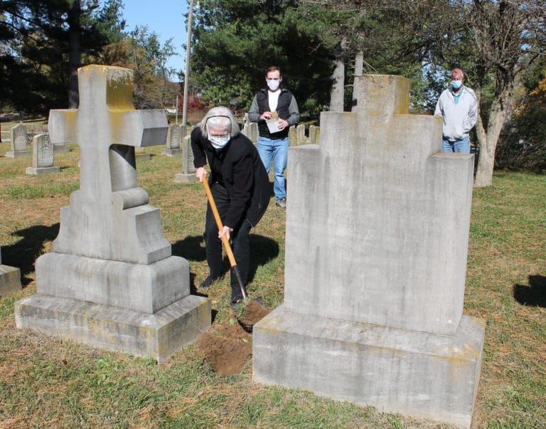 Ursuline Sister Nancy Liddy, a member of the Archives staff in Maple Mount, replaces the soil to complete the burial of the prayer cards. In back are Mike Bogdan, right, and Edward Wilson.