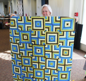 Deb Rutherford holds up the three-dimensional quilt she began working on the day before.