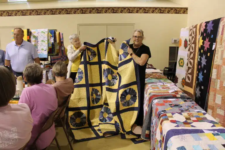 Jamie Bittel of Utica holds up the beautiful Dresden Plate quilt she chose, with help from Sister Jane Falke. This quilt was pieced by Mary Garcia, quilted by the late Sister Amelia Stenger, and bound by Sister Elaine Burke. Jamie Bittel of Utica holds up the beautiful Dresden Plate quilt she chose, with help from Sister Jane Falke. This quilt was pieced by Mary Garcia, quilted by the late Sister Amelia Stenger, and bound by Sister Elaine Burke.