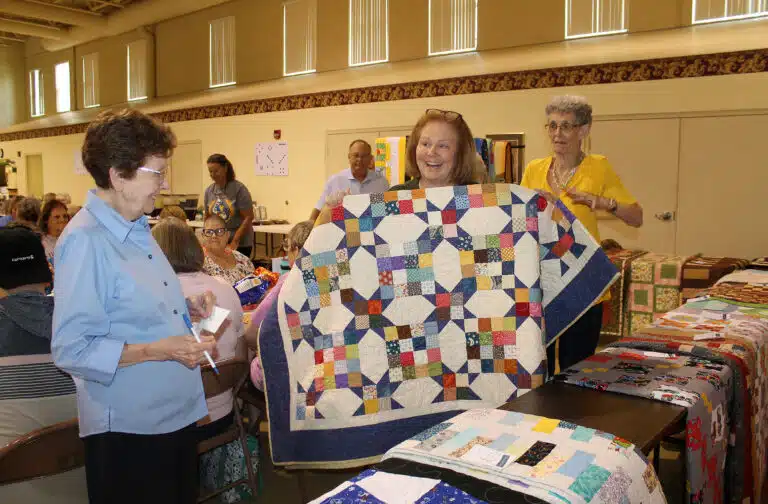Jami Sandusky of Lebanon, Ky., was back with a second bingo win in round six. She was excited to win “Arrows and Angles.” Sister Mary Henning at left smiles as Jami holds up the quilt. Jami Sandusky of Lebanon, Ky., was back with a second bingo win in round six. She was excited to win “Arrows and Angles.” Sister Mary Henning at left smiles as Jami holds up the quilt.