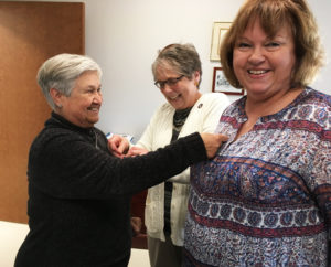 Ursuline Associates Elaine Wood, left, Stephanie Render, center, and Martha Little joke around with pinning each other with their associate pins. One of them forgot her pin.