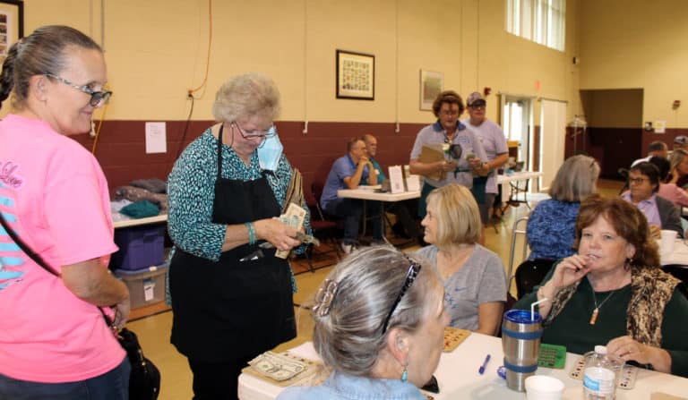 Associate Suzanne Reiss, second from left, collects money as she sells bingo cards. Most games were $1 per card, with some larger quilts eligible in the $2 games.