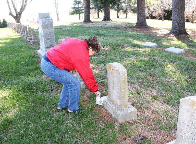 Aloma Dew places a flag on the grave of Sister Mary Michael Barrow. She was the first dean of the Mount Saint Joseph Junior College, wrote “Candles of the Lord,” the history of the first 25 years of Ursuline ministry in New Mexico, and was instrumental in opening Brescia College in Owensboro.