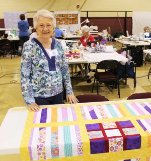 Billie Simpson, of Guntersville, Ala., poses with the colorful quilt of her own design that she’s making for her 13-year-old granddaughter.