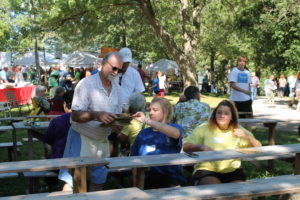 A volunteer hands out bingo cards at the bingo area of the picnic. The booth is run by Immaculate Parish in Owensboro.