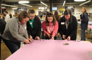 Sister Monica Seaton, far right, and Brescia students cut the edges of two pieces of fleece.