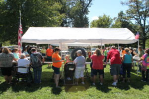 Several people gathered at the Cake Wheel booth, including Sister Carol Shively, center (in front of the wheel).