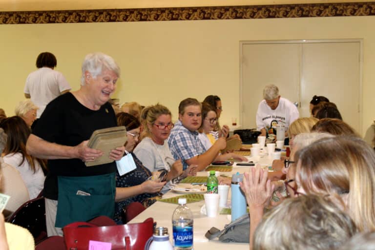 Sister Suzanne Sims smiles as she holds a stack of bingo cards.