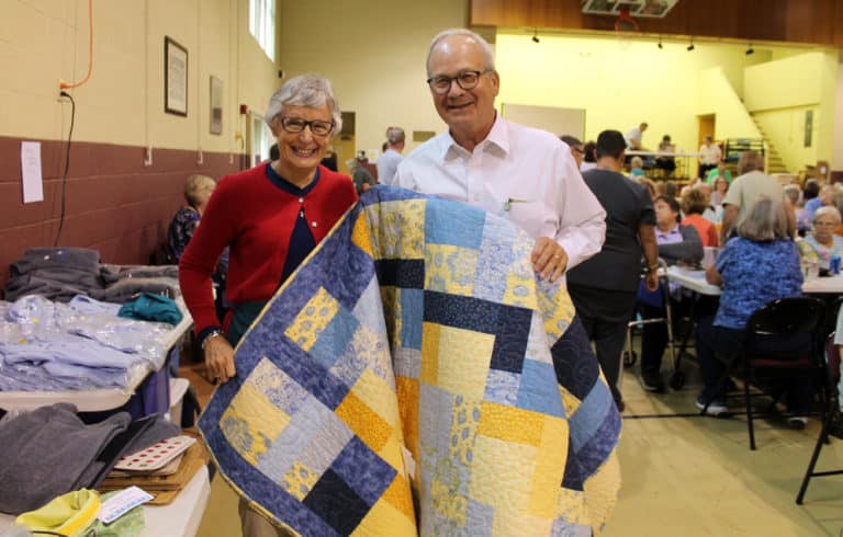 Associate Carolyn McCarty and her husband John pose with the quilt John won.