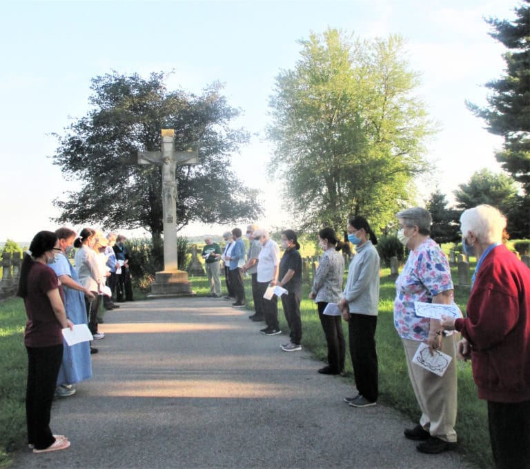 Sisters gather to pray in front of the crucifix that welcomes visitors to the cemetery and sing the traditional hymn, “Holy Ground.”