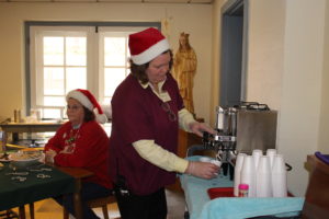 Elaine Foster pours a cup of hot apple cider to go with the treats. At left is Sheila Blandford.