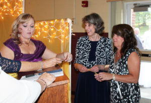 Betsy Mullins, left, director of Development for the Ursuline Sisters, tells guests Charlotte Hedges, center, and Sonya Evans their table number. Hedges and Evans both work for the Diocese of Owensboro, which sponsored a table.