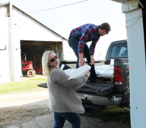 Chelsea Williams, program director for Agricultural Studies at OCTC, helps John Robert Murphy unload bags of feed from her truck on April 14. The pigs eat a mixture of ground corn, vitamins and soybean meal. The 17 pigs eat 1,000 pounds a week, Williams said.