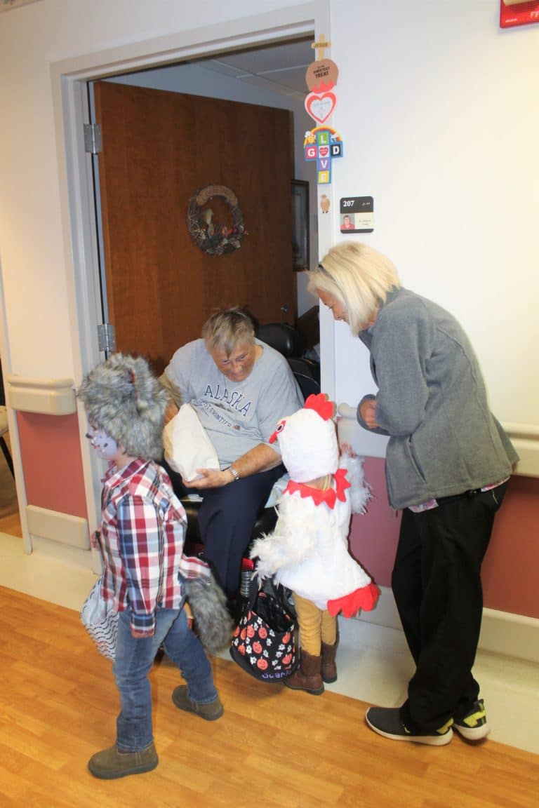 Sister Dee Long gets ready to give candy to “Chicken Little” Scarlett, granddaughter of Jenny Lageson who works in Health Care in the Villa. At left is “Wolf” Emmitt, who is also Jenny’s grandchild.