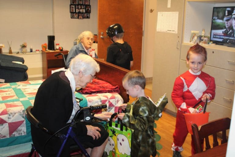 Sisters Clarita Browning, left, and Marie Goretti Browning get three trick or treaters at once – “Dinosaur” Kaiser, “Swat Team Cop” Brentley, and “Power Ranger” Asher.