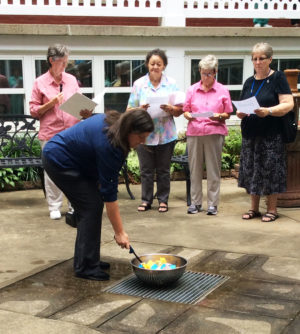 Sister Monica Seaton sets fire to the bowl of prayers and reflections to let them act as incense for the prayer service. Standing from left are Sisters Mary Ellen Backes, Evelyn Latham, Judith Nell Riney and Betsy Moyer.