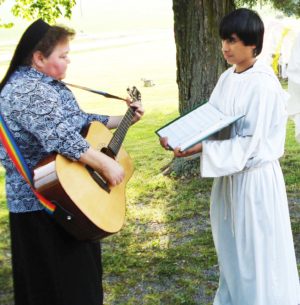 Sister Alicia Coomes plays her guitar as server Michael Turner holds her music during the Feast of Corpus Christi at St. Ambrose Church, Henshaw, Ky.