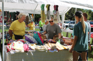 Volunteer Barbara Fischer, left, smiles as she waits on customers in the Crafts booth.