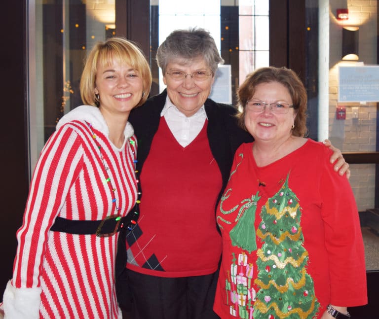 Dressed in Christmas cheer, Rachel Besing, left, and Vicki Tinsley, both psychology professors at Brescia, wish Sister Cheryl well.