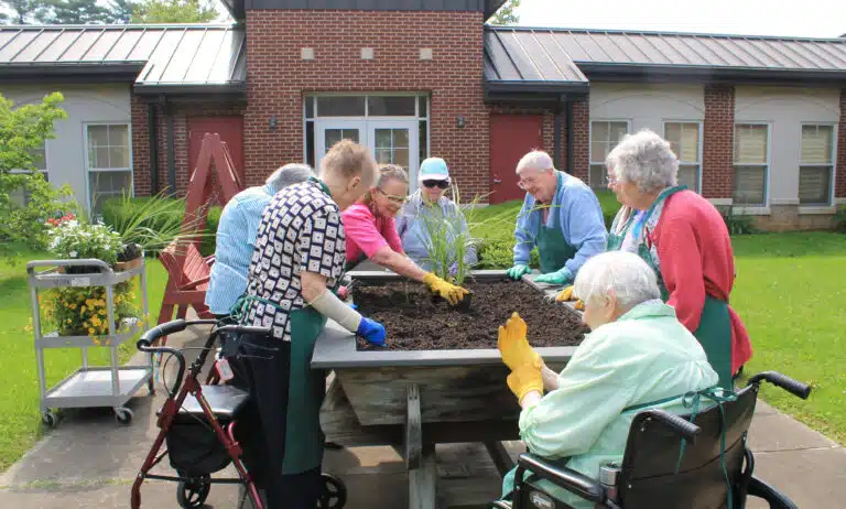 Employee Ashley Wilkerson determined that the first things to be planted in the raised bed were dracaena or “spikes.” These were the tallest, so they were placed in the center. Looking on, left to right, are Sisters Marie Carol Cecil, Luisa Bickett, Marie Joseph Coomes, Grace Simpson, Joyce Cecil, Mary Gerald Payne, and Sheila Anne Smith.