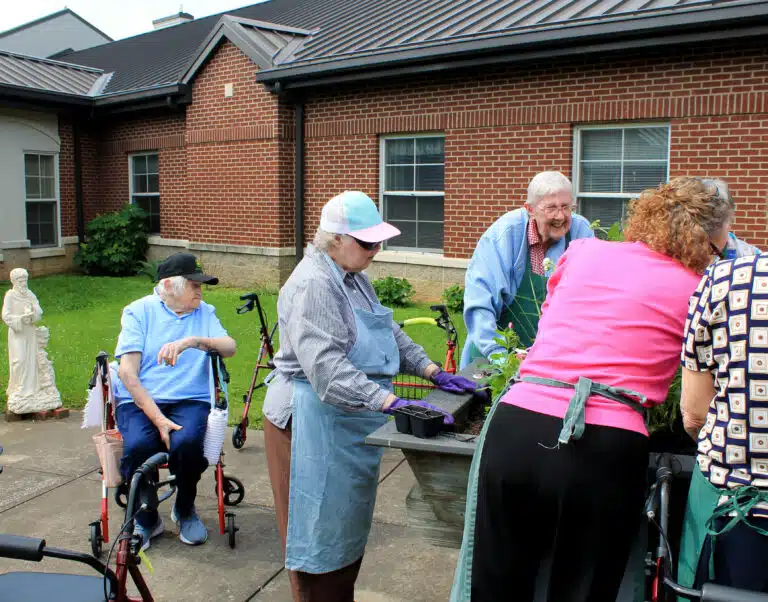 Sister Catherine Kaufman, left, watches as Sister Marie Joseph Coomes, center, Sister Grace Simpson and others decide where to place the flowers. Sister Catherine has spent many years helping to take care of the plants at Mount Saint Joseph.