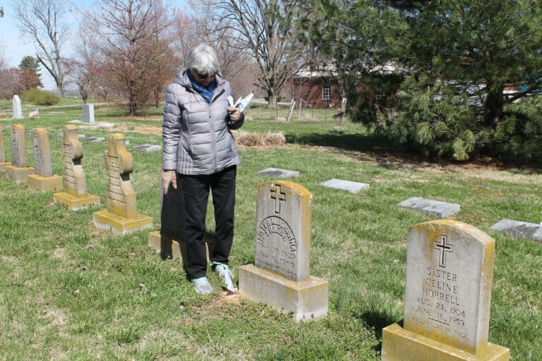 Judy Adams views the grave of Sister Johanna Froeba after placing a flag next to her head stone. Sister Joanna was one of the five pioneer Ursulines who traveled by flatboat down the Ohio River from Louisville to open Mount Saint Joseph Academy in 1874.