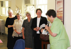 New Council members, from left, Sisters Pat Lynch, Judith Nell Riney, Pam Mueller and Amelia Stenger laugh in the dining room as Sister Sharon Sullivan presents them with a gift basket, which included items such as chocolate, gift cards and ibuprofen.