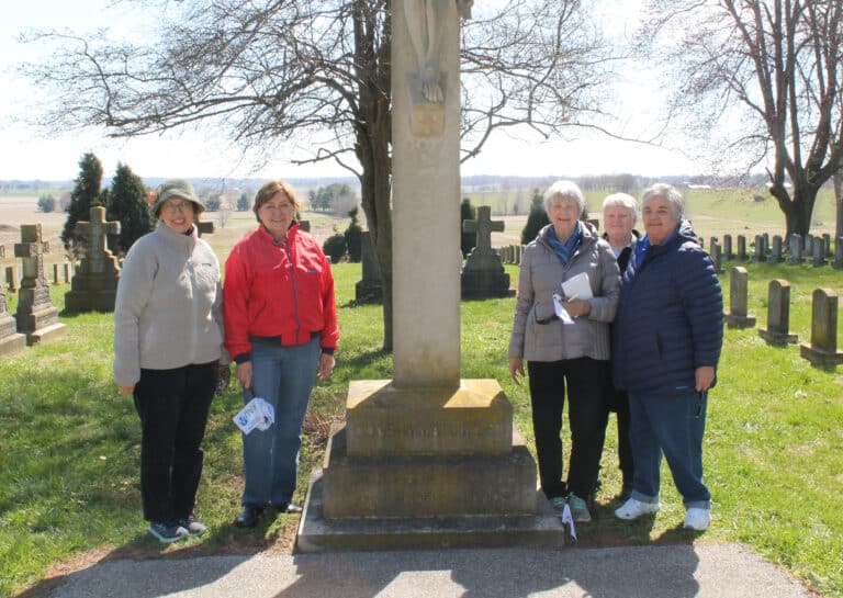 The AAUW members joining Sister Suzanne Sims (second from right) in the Mount Cemetery are, from left, Edna Murphey, Aloma Dew, Judy Adams and Merry Miller.
