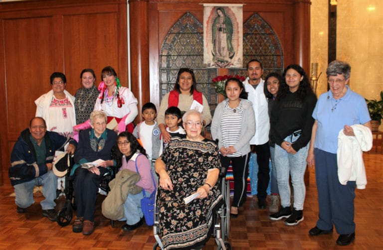 Several visitors gather for a photo with, front row: Sister Fran Wilhelm, second from left, Sister Sara Marie Gomez, seated in center, and Sister Luisa Bickett, far right.