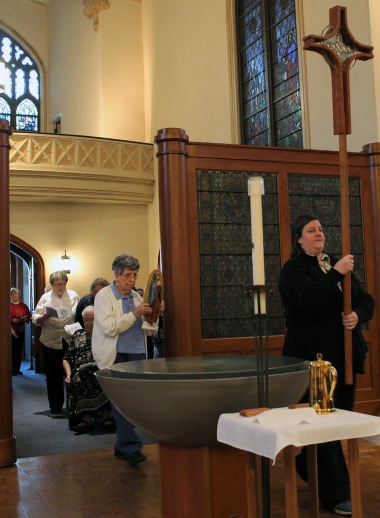 Sister Monica Seaton, right, carries in the processional cross. She was followed by Sister Luisa Bickett with a statue of Our Lady of Guadalupe.