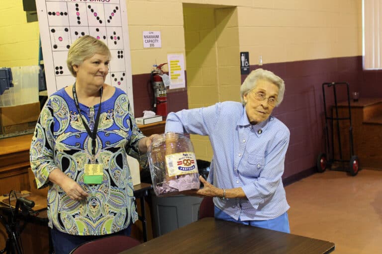 Carol Braden-Clarke, director of development for the Ursuline Sisters, holds the Half Pot container as Sister Elaine Burke averts her gaze and draws a winner.