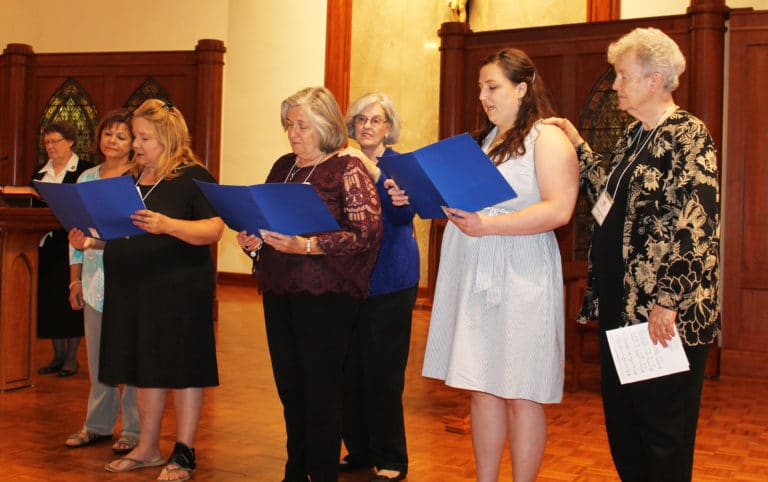 The three new Ursuline Associates read their commitments, while being joined by their contact companion. From right, Sister Michele Morek is with new Associate Renee Schultz; Associate Pauline Goebel is with new Associate Marian Pusey; and new Associate Lori Haynes is joined by Associate Debbie Lanham. Sister Amelia Stenger, congregational leader, is at left.