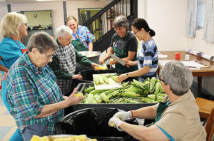 Even “corny” jokes make the sisters and kitchen staff laugh, as is evident in this photo as sweet corn from the farm is processed. Around the table starting at right is Ursuline Sister Mary McDermott, Sister Huyen Vu, (a Sister of the Lovers of the Holy Cross who is staying at the Mount), Sister Jacinta Powers, Melody Payne (food service manager), Sister Marie Bosco Wathen, Mary Lykins (food service employee) and Sister Susanne Bauer.