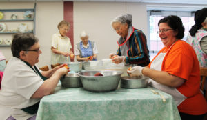 Sister Stephany Nelson, right, laughs as she peels peaches with Sister Grace Swift, center, and Sister Lois Lindle, left. In the background are Sister Marie Carol Cecil (left) and Sister Clarita Browning.