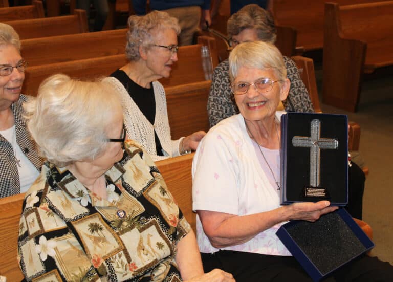 Sister Mary Celine holds her gift from the parish and school as Sister Pat Rhoten, left, admires it. The plaque reads, “Sr. Mary Celine Weidenbenner, thank you for serving the Catholic school and parish community of Knottsville, Kentucky. Congratulations on your 60th jubilee of religious life.”
