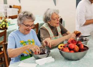 Sister Ann Patrice Cecil, left, chuckles at a comment made by Sister Catherine Barber as they peel peaches.