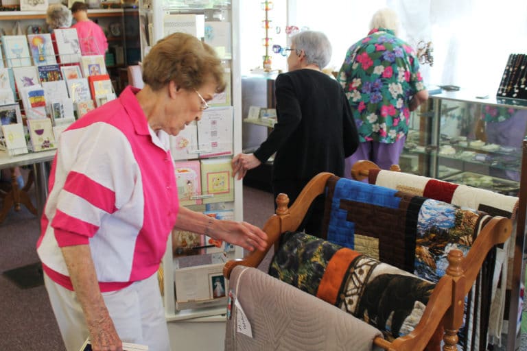 Sister Elaine Burke admires some of the quilts for sale in the shop.
