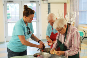 Ursuline Associate Doreen Abbott, left, leader of the Whitesville Y-DOSA group, cuts peaches with Sister Mary Jude Cecil, center, and Sister George Mary Hagan in the small dining room.