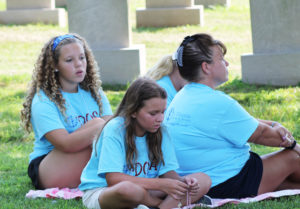 Taylor Pedley, left, and Paige Crabtree, both of Whitesville, join Whitesville assistant leader Julie Foster in singing the Chaplet of Divine Mercy in the cemetery.