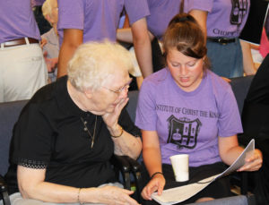 Sister Mary Agnes VonderHaar studies the curriculum for the camp with this young lady.