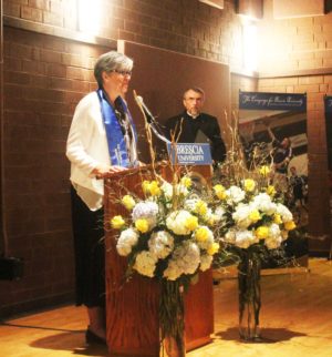 Sister Larraine speaks to the audience as she accepts her honor. Father Larry Hostetter, Brescia president, is in the background.