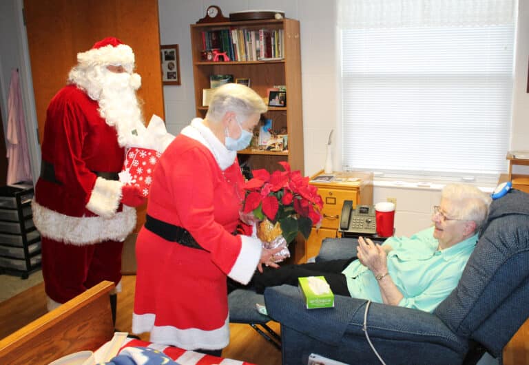 Sister Eva Boone smiles as she receives instructions on caring for her poinsettia from Mrs. Claus.