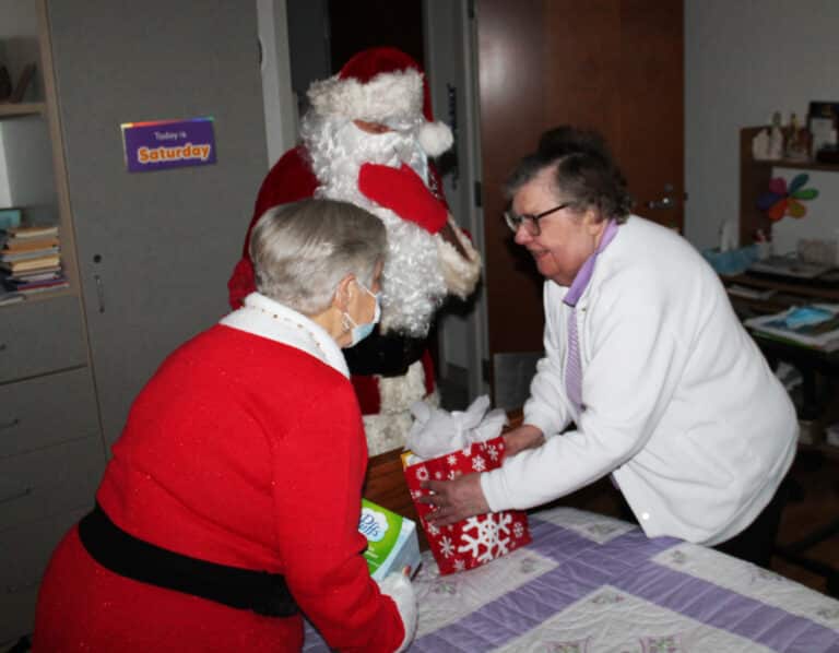 Sister Paul Marie Greenwell is all smiles as she receives her bag of treats from Santa and Mrs. Claus.