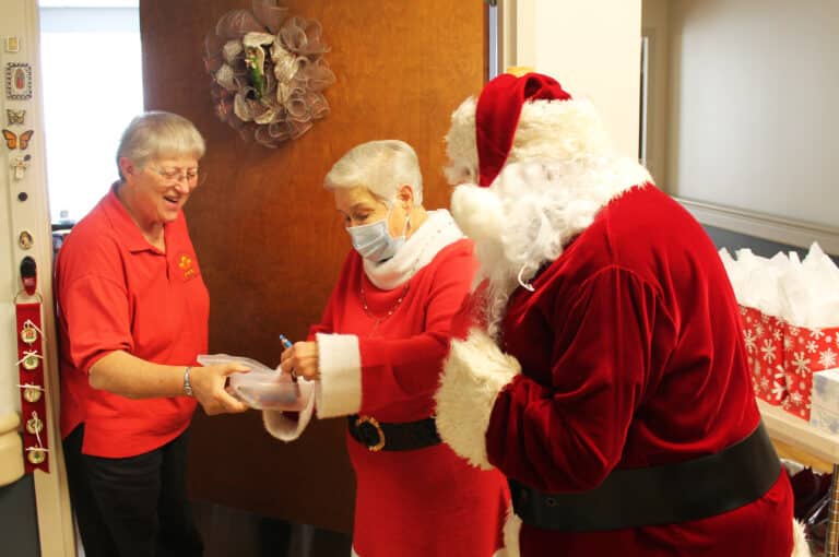 Sister Emma Anne Munsterman turns the tables and offers Santa and Mrs. Claus a present of an Ursuline ink pen.