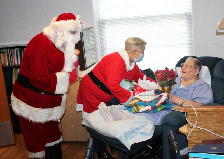 Sister Kathleen Dueber smiles as she receives her poinsettia and candy from the Western Kentucky Associates.